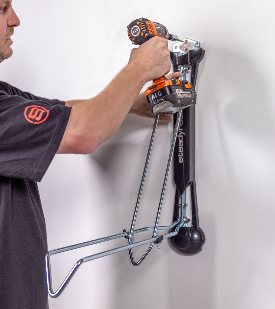 A person using a drill to install a Steadyrack bike rack.