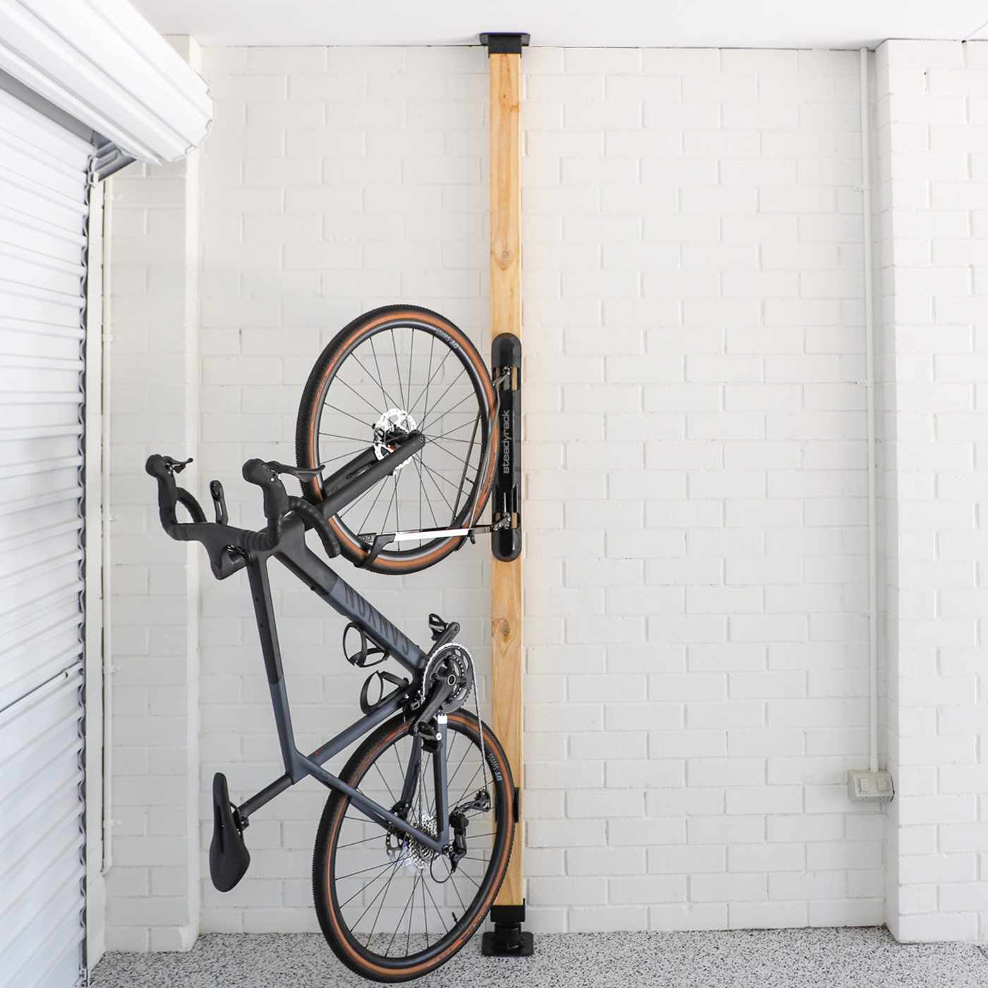 Bicycle mounted on a wall rack against a white tiled wall.