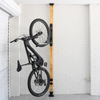 Bicycle hanging on a wall-mounted rack against a white tiled wall.