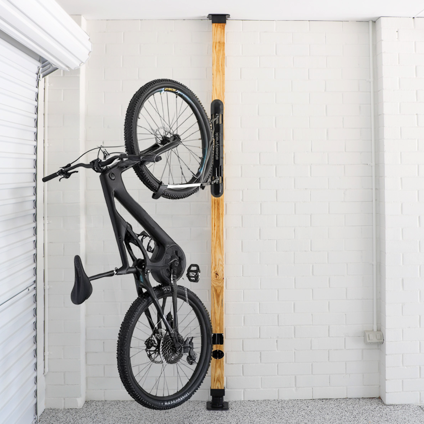 Bicycle hanging on a wall-mounted rack against a white tiled wall.