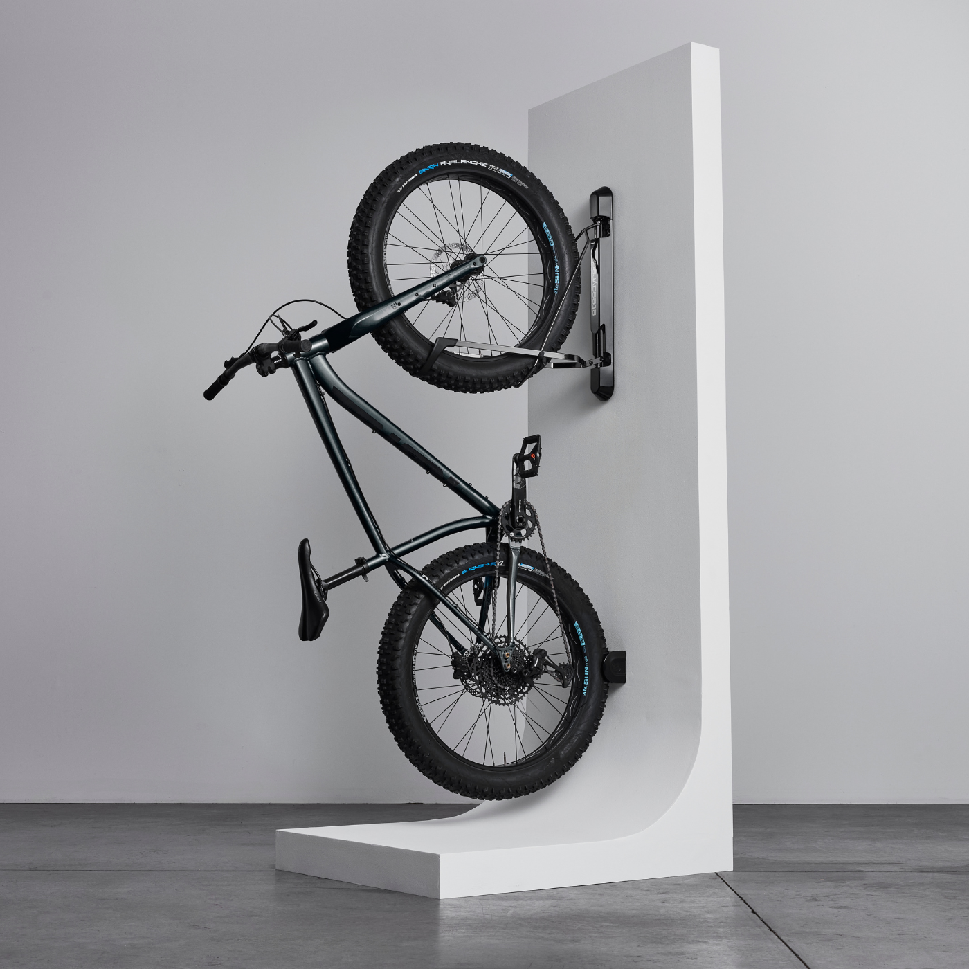 Bicycle mounted on a white wall-mounted rack against a plain background